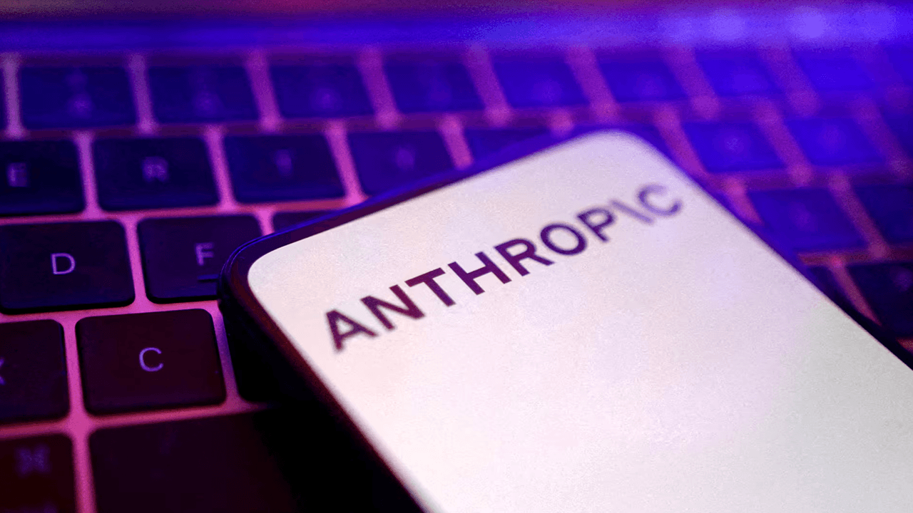 A smartphone displaying the Anthropic logo rests on a laptop keyboard illuminated by purple and blue lighting.