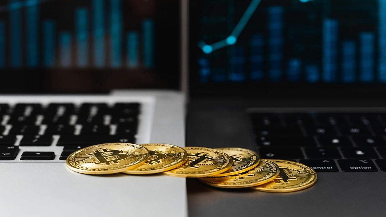 Physical BTC tokens lying on two laptops