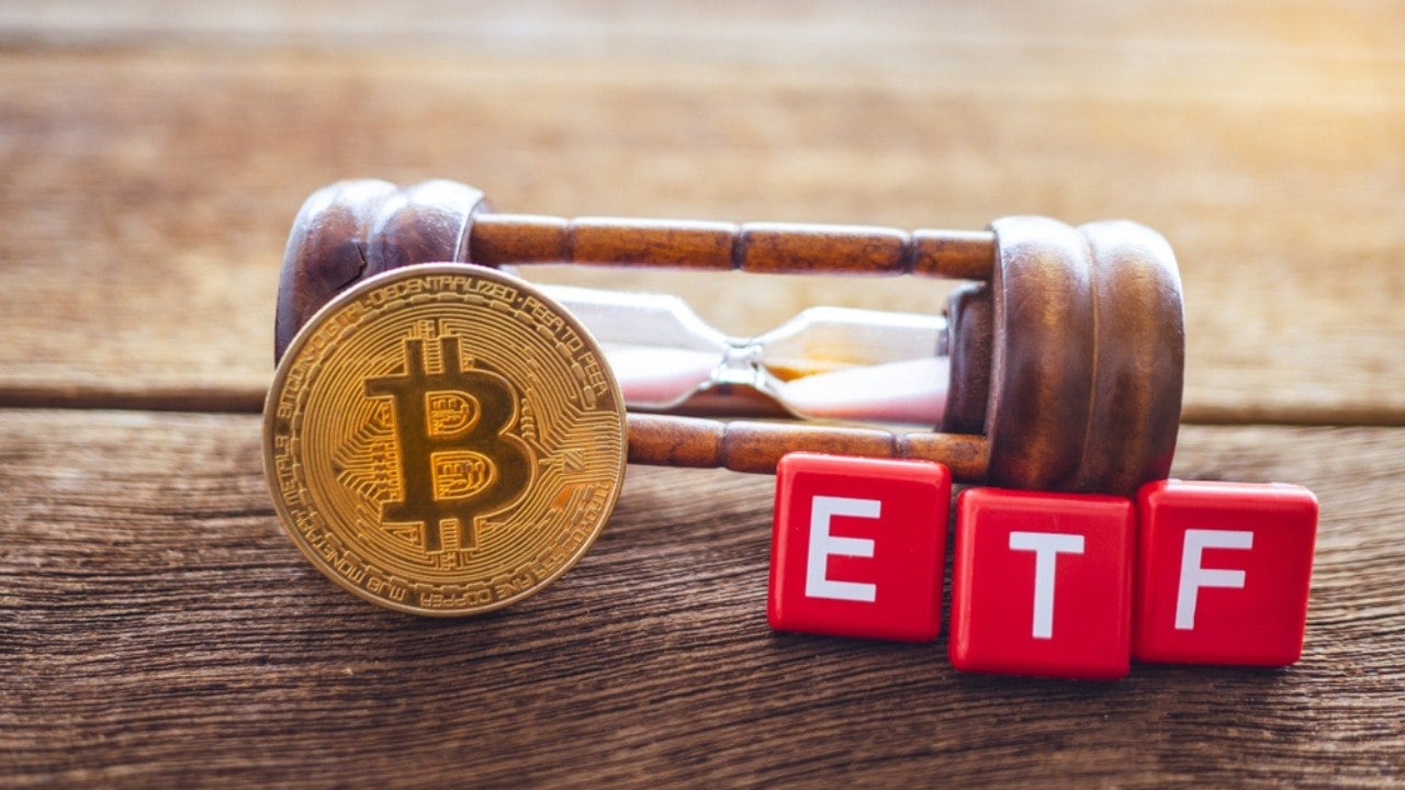 Bitcoin with ETF text on blocks, resting on hourglass