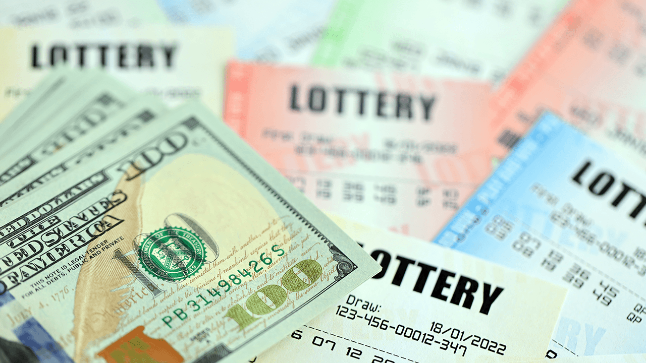 $100 bills and lottery tickets on a desk.