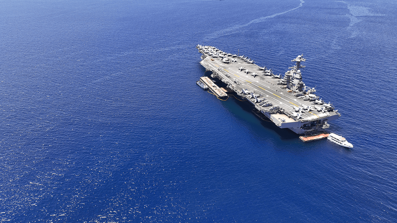 A U.S. aircraft carrier sits in the Pacific Ocean with support vessels alongside.