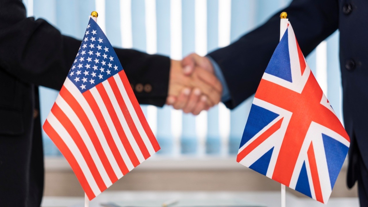 US and UK flags with men shaking hands